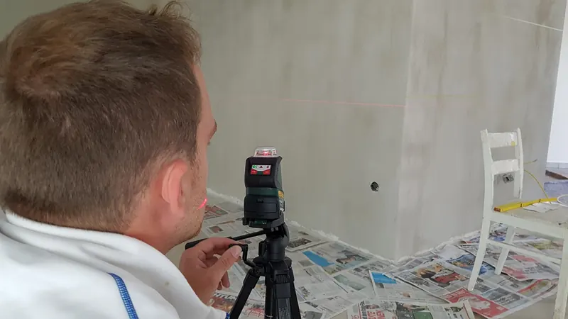 Malermeister richtet eine Wand mit dem Linienlaser aus